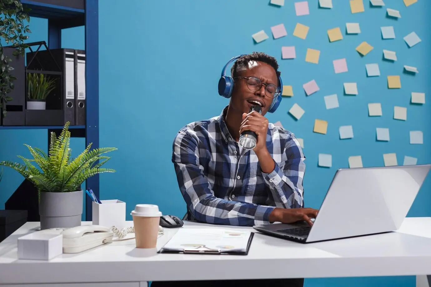 Empleado alegre en la oficina de una empresa de marketing, con auriculares inalámbricos modernos, escuchando música y cantando. Hombre de negocios feliz y positivo sentado en el escritorio de su espacio de trabajo mientras disfruta de la canción.